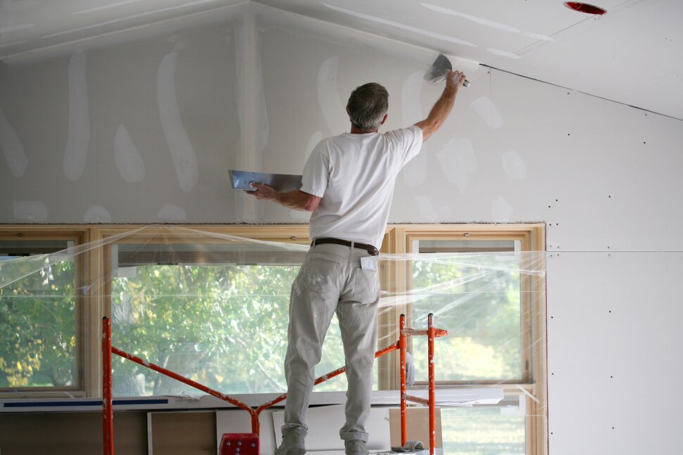 A man is painting the ceiling of a house