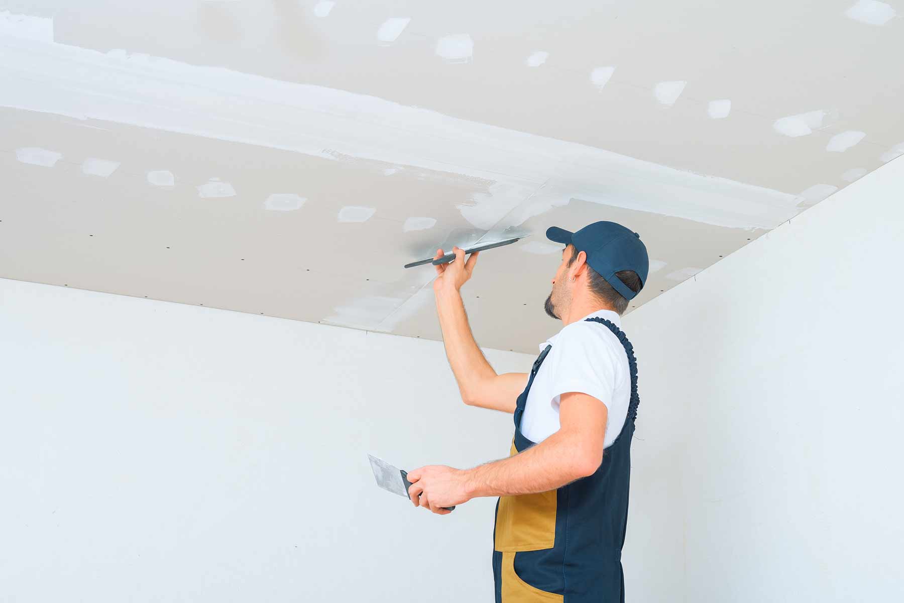 A man painting a ceiling with a paint roller