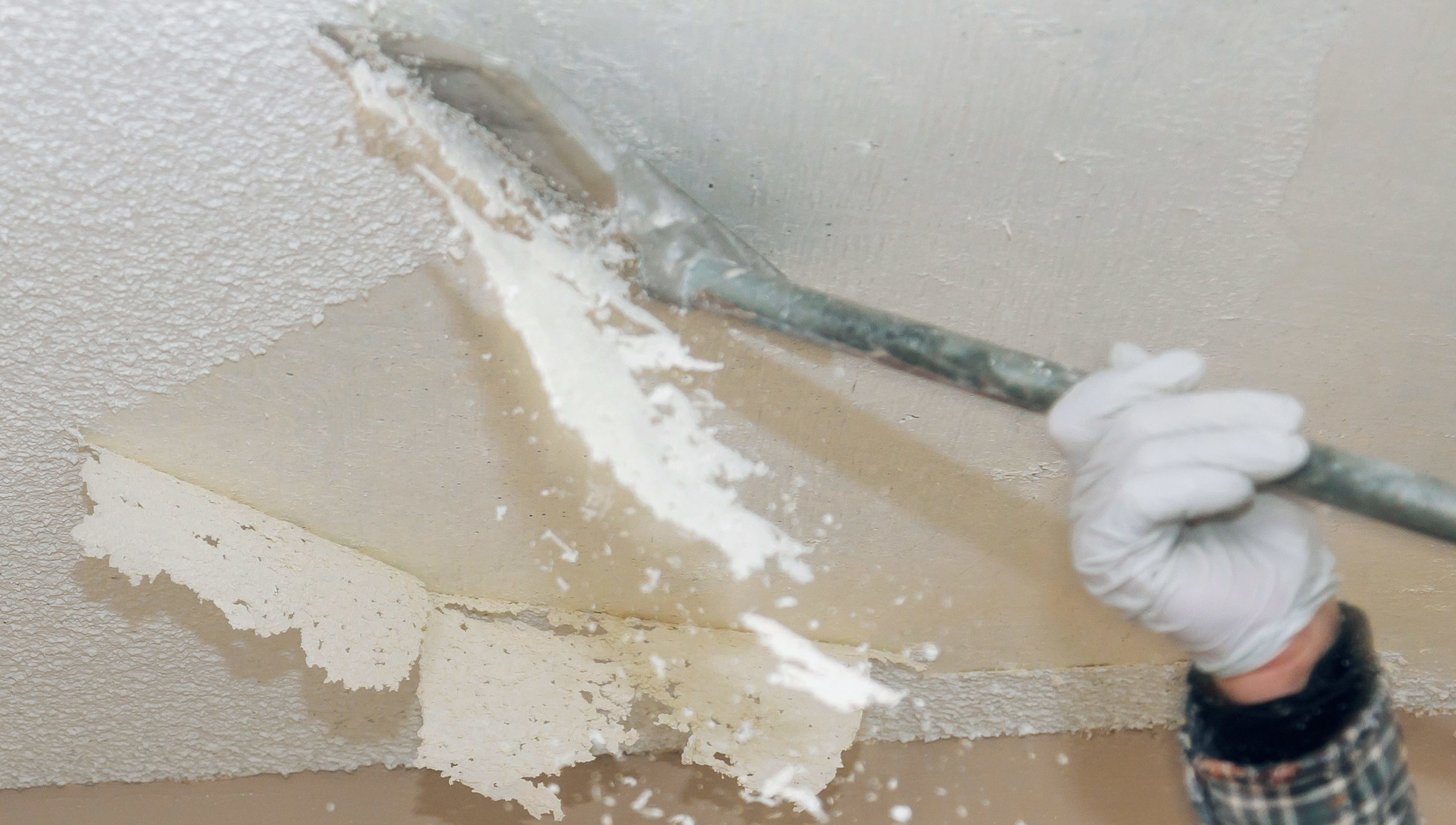 A person in white gloves and white gloves painting a ceiling