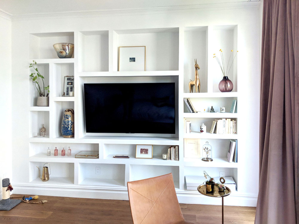 A living room with a large tv and shelves